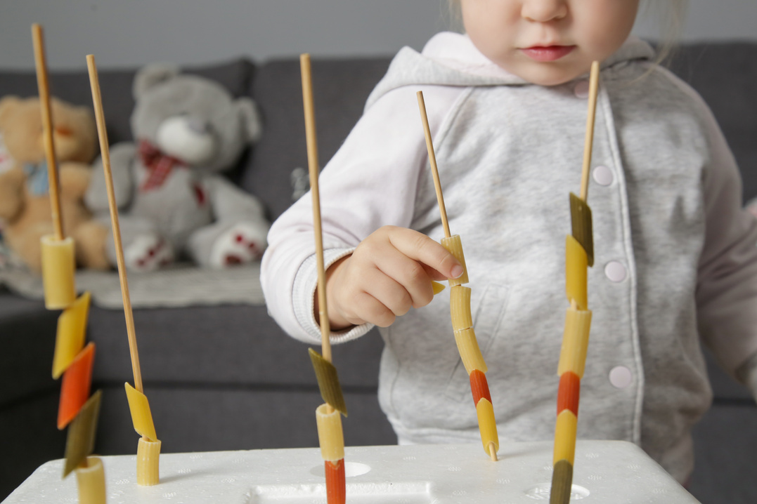 Fine motor pasta threading activity for kids. An easy and fun tower building challenge that works on fine motor skills as well as hand eye coordination.